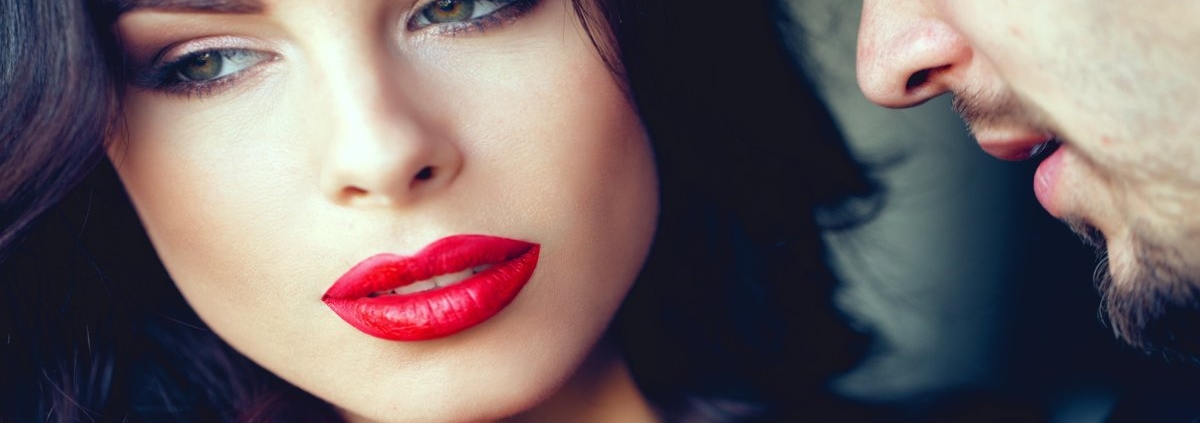 Close-up of a glamorous woman in red lips as a man whispers into her ear, symbolizing secret Vegas nightlife